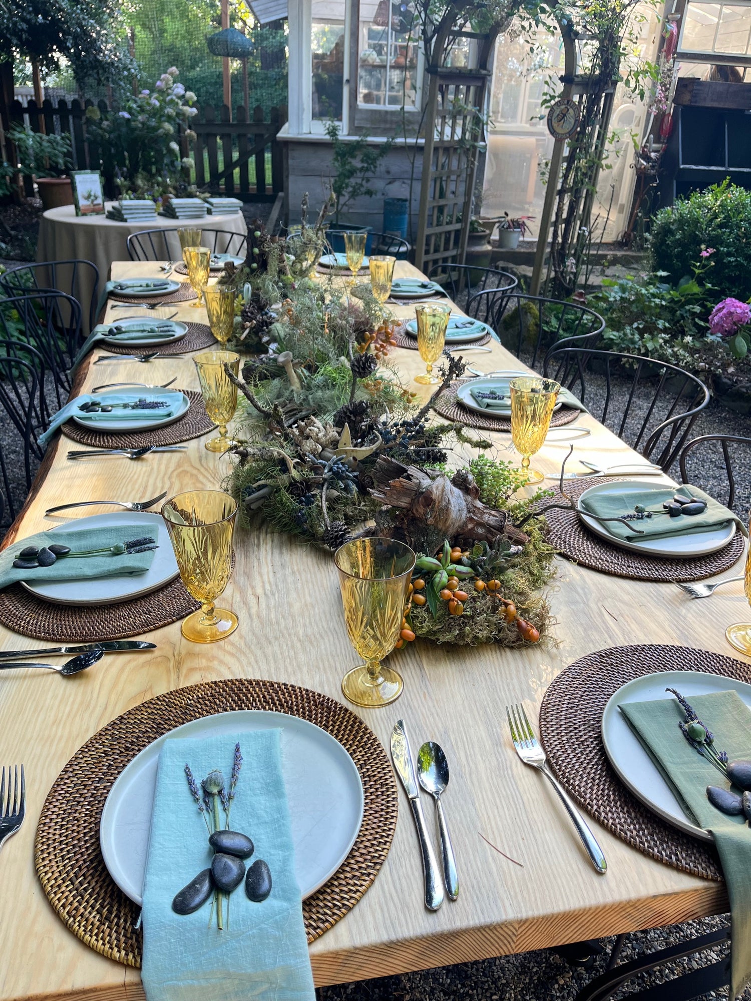 10' by 4' Ponderosa pine table laden with dishes upon placemats with an flatteringly rustic flower arrangement in the center.